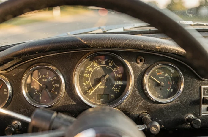 Gros plan sur le tableau de bord vintage d'une voiture avec compteur de vitesse et tachymètre analogiques, symbolisant la puissance en chevaux et la vitesse